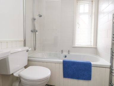 A bathroom with a toilet a bathtub with shower and a blue towel on the side at ODYSEA Weymouth