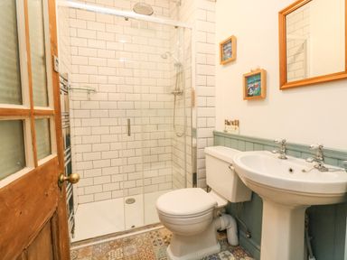 A bathroom with a shower cubicle toilet and sink with a wooden framed mirror at ODYSEA Weymouth