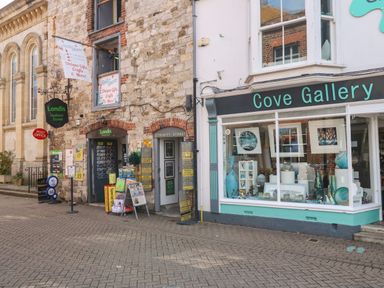 Street view with Londis Harbour Stores and Cove Gallery with art pieces in windows at ODYSEA Weymouth