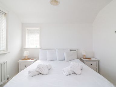A bedroom with a bed with white linens and towels on it and two bedside tables with lamps at ODYSEA Weymouth