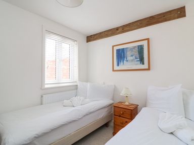 A bedroom with two single beds a wooden bedside table and a framed picture on the wall at ODYSEA Weymouth
