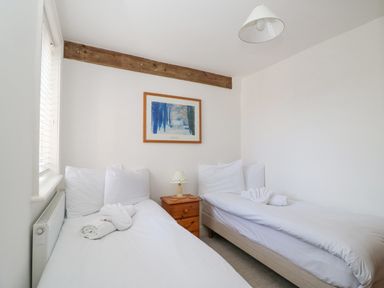 A bedroom with two single beds a wooden bedside table and a framed picture on the wall at ODYSEA in Weymouth