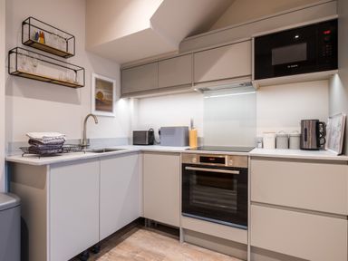 A kitchen with grey cabinets a built in oven and microwave a sink and countertop appliances at Howe Keld 1 Ground floor in Keswick