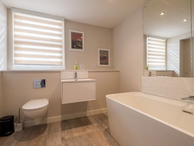 A bathroom with a bathtub a wall-mounted toilet a sink a large mirror and two framed pictures Howe Keld 1 Ground floor Keswick