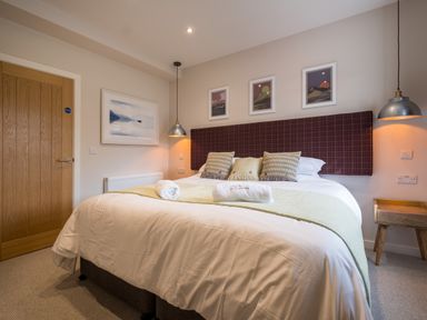 A bedroom with a double bed pillows hanging lamps and framed pictures on the wall at Howe Keld 1 Ground floor in Keswick