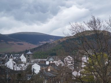 A town with houses and a stone tower with hills and cloudy sky in the background at Howe Keld 4 First floor in Keswick