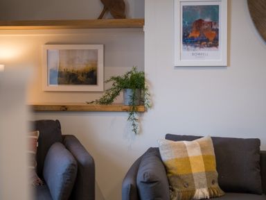 A living room with two gray sofas a plaid cushion a plant on a wooden shelf and framed pictures on the wall at Howe Keld 4 First floor in Keswick