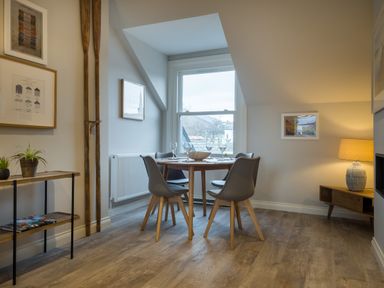 A dining area with a round table set with four chairs near a window at Howe Keld 4 First floor in Keswick