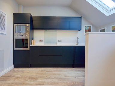 A kitchen with black cabinets a built-in oven and microwave a sink under a skylight at Howe Keld 4 First floor in Keswick