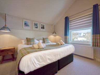 A bedroom with a double bed bedside table hanging lights and a window with curtains at Howe Keld 4 First floor in Keswick