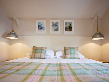 A bedroom with two hanging lamps above a bed with plaid pillows and blanket at Howe Keld 4 First floor in Keswick