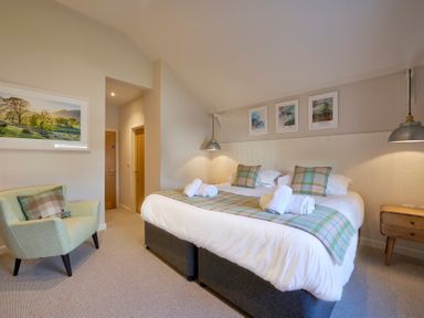 A bedroom with a double bed armchair and framed pictures on the wall at Howe Keld 4 First floor in Keswick
