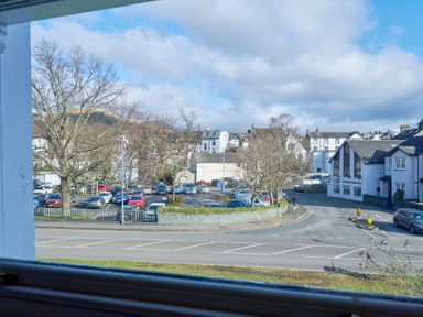 A view of a parking lot with cars trees and buildings across a street at Howe Keld 4 First floor in Keswick