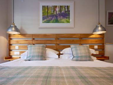 A bedroom with a wooden headboard two bedside lamps and a framed picture above the bed at Howe Keld 4 First floor in Keswick