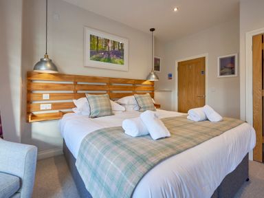 A bedroom with a double bed wooden headboard and pendant lights at Howe Keld 4 First floor in Keswick