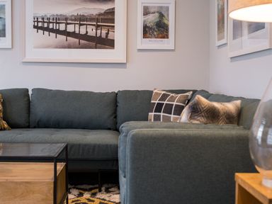 A corner sofa with cushions and framed pictures on the wall above at Howe Keld 5 First Floor in Keswick
