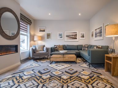 A living room with a sectional sofa armchair coffee table and wall art at Howe Keld 5 First Floor in Keswick