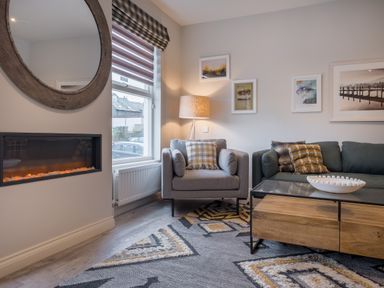 A living room with an armchair sofa coffee table and wall art at Howe Keld 5 First Floor in Keswick