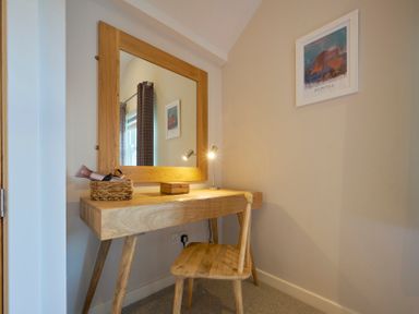 A wooden desk with a wicker basket holding a hair dryer a small lamp and a wooden chair at Howe Keld 5 First Floor in Keswick