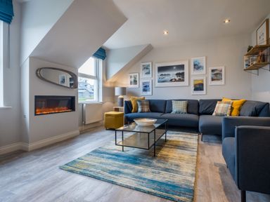 A living room with a fireplace a blue sofa and a glass coffee table at Howe Keld 6 Second Floor in Keswick