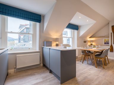 A kitchen and dining area with a wooden table set with glasses and plates at Howe Keld 6 Second Floor in Keswick