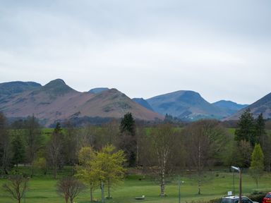 A landscape with trees and grass in the foreground and hills in the background at Howe Keld 6 Second Floor in Keswick