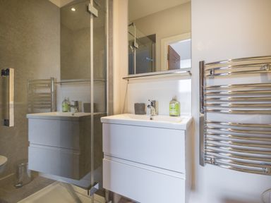 A bathroom with a white sink cabinet a mirror a chrome heated towel rail and a glass shower enclosure at Howe Keld 6 Second Floor in Keswick
