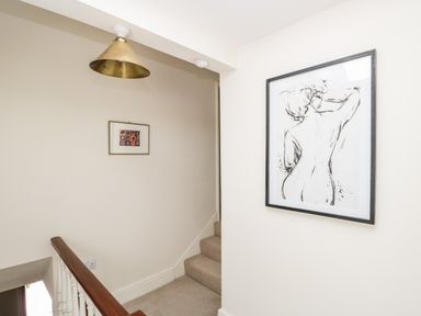 A stairway with two framed artworks on the walls and a brass ceiling light at Caldhu Cottage in Holmrook