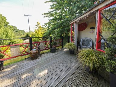 A wooden deck with potted plants and a small seating area at Cherry Pod in Hookagate near Meole Brace