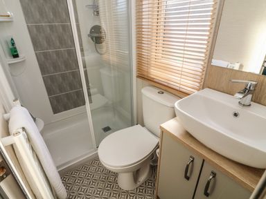 A bathroom with a shower enclosure toilet sink with cabinet and window blinds at Elim South Lakeland Leisure Village near Tewitfield