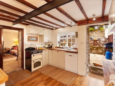 A kitchen with a stove dishwasher and wooden countertops opening to a stone patio at Southcott Farm Cottage in Sheldon