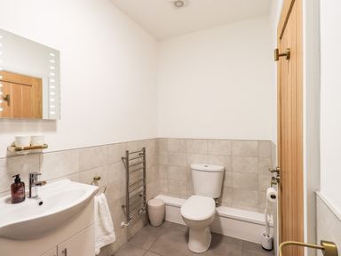 A bathroom with a white toilet sink a towel rail and a wooden door at Aryelle House in Kendal