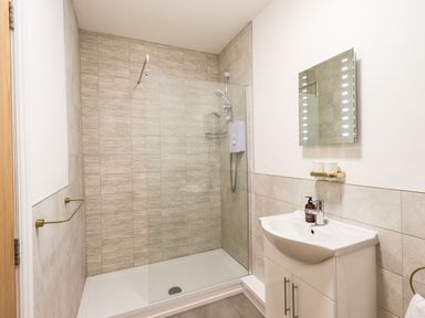 A bathroom with a walk-in shower and a sink with a mirror at Aryelle House in Kendal