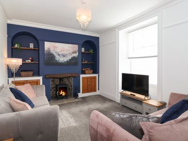 A living room with a fireplace between built in shelves sofas and a television at Aryelle House in Kendal