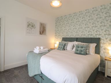 A bedroom with a large bed with pillows and folded towels on a blanket at Aryelle House in Kendal