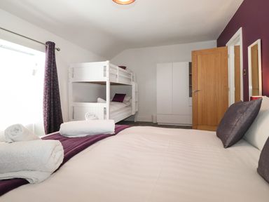 A bedroom with a double bed and bunk beds a white wardrobe and a wooden door at Aryelle House in Kendal
