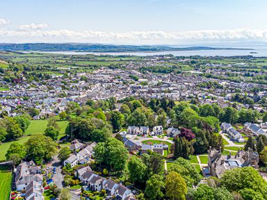An aerial view of a town with houses trees and fields near a body of water at The Mabel Suite Stone Cross Mansion Ulverston