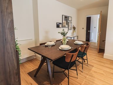 A dining room with a wooden table set for four with plates glasses and cutlery at The Mabel Suite Stone Cross Mansion in Ulverston