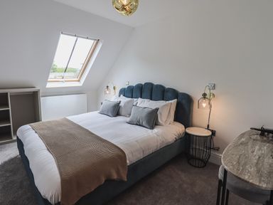 A bedroom with a bed a skylight window and bedside tables at The Mabel Suite Stone Cross Mansion in Ulverston
