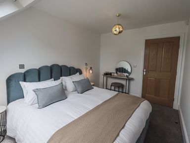 A bedroom with a bed table a round mirror and a wooden door at The Mabel Suite Stone Cross Mansion Ulverston