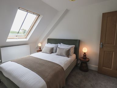 A bedroom with a double bed pillows bedside tables with lamps and a skylight window at The Mabel Suite Stone Cross Mansion in Ulverston