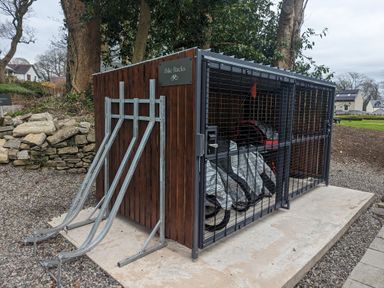 A locked outdoor bike storage unit with covered bicycles inside