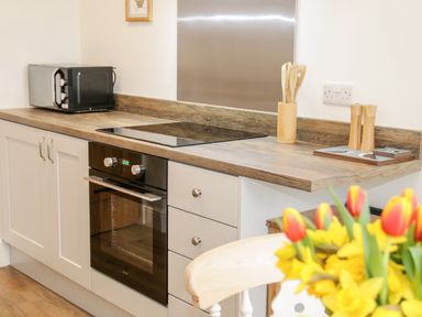 A kitchen counter with a microwave oven stove and wooden utensils at The Old Stable in Henryd near Conwy