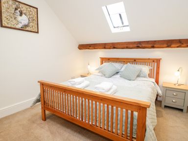A bedroom with a wooden bed frame and skylight at The Old Stable in Henryd near Conwy