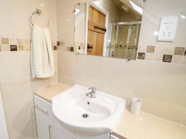 A bathroom sink with a towel on a ring holder and a mirror above at The Old Stable in Henryd near Conwy