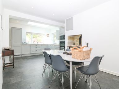 A kitchen with gray cabinets and black chairs around a white table at The Headland in Llaneilian near Amlwch