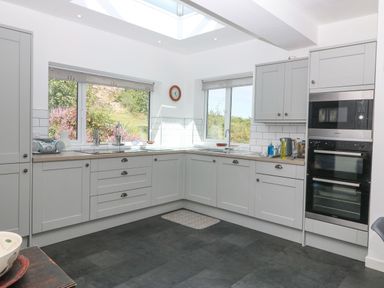 A kitchen with grey cabinets a double oven windows and a skylight at The Headland in Llaneilian near Amlwch
