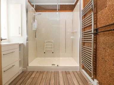 A bathroom with a walk-in shower bench and heated towel rail at The Headland in Llaneilian near Amlwch