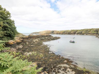 A coastal inlet with rocky shores and boats on the water at The Headland in Llaneilian near Amlwch