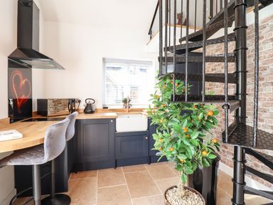 A kitchen with black cabinets a wooden countertop a spiral staircase and a potted plant at Glyndwr in Betws-Y-Coed